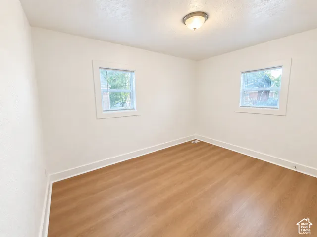 Warm wood-finish flooring, white walls, and two windows