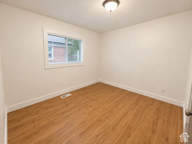 Wood-finish flooring, white walls, white trim, window with blinds, and ceiling-mounted light fixture