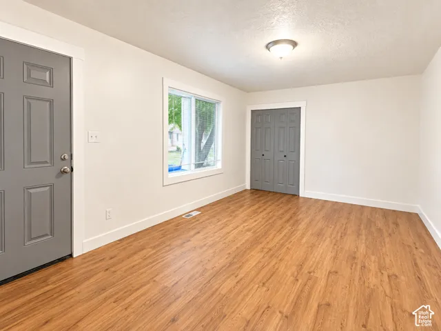 Wood-finish flooring, white walls, and a window with white trim