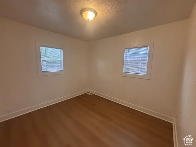 Wood-finish flooring, white trim, two windows with blinds, and an overhead flush-mount light fixture