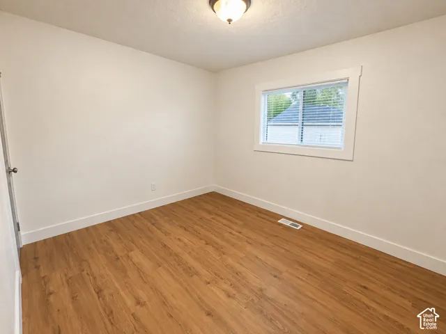 Wood-finish flooring, white trim, recessed window with blinds, and ceiling-mounted light fixture