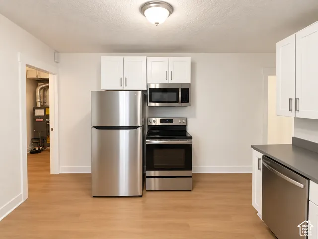 Kitchen featuring wood-finish flooring, white cabinetry, and stainless steel appliances