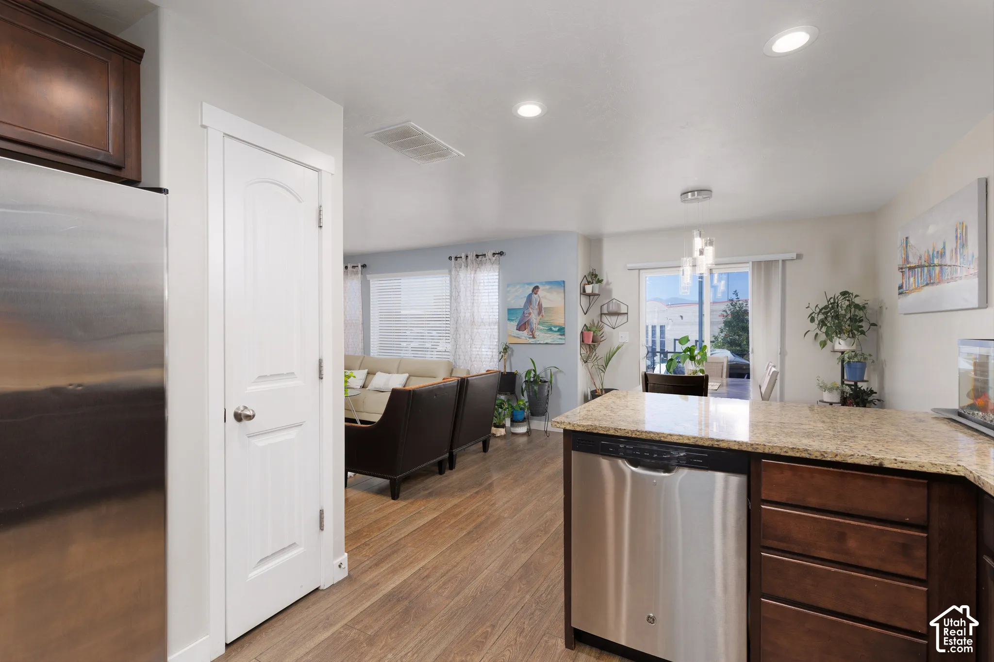 Kitchen island with granite countertop, wood-finish flooring, stainless steel dishwasher, and recessed lighting