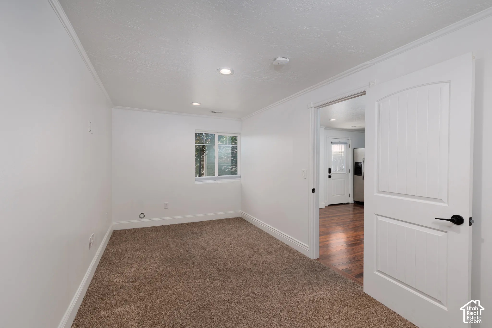 Recessed lighting, white trim, window, wall-to-wall carpeting, and a white interior door with black hardware