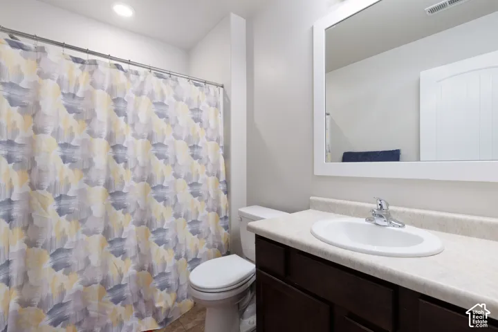 Recessed ceiling lighting, wood-finish flooring, built-in vanity with single basin sink, wall-mounted mirror, and white paneled door