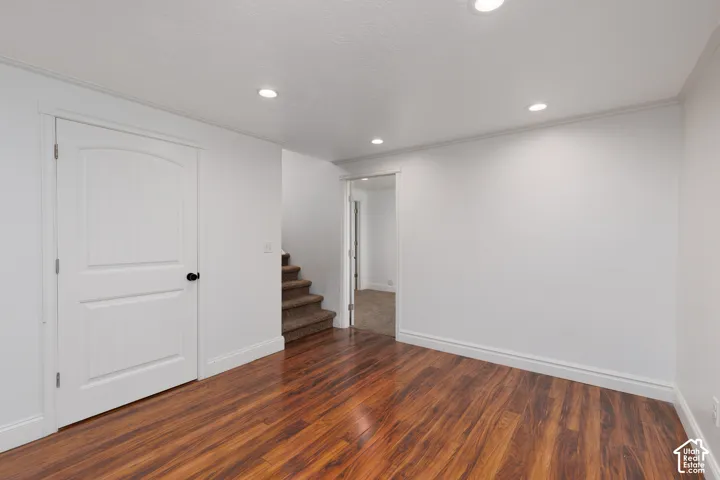 Wood-finish flooring, recessed lighting, white interior door with arched paneling, staircase with carpeted treads