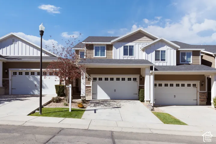 Two-story townhouse with a stone and siding exterior, featuring multiple windows with white trim, and an attached two-car garage