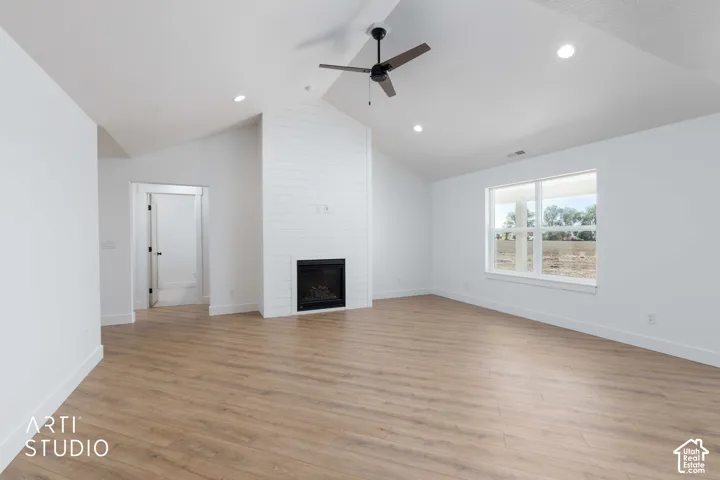 Vaulted ceilings with recessed lighting, wood-finish flooring, white shiplap fireplace surround, and a ceiling fan
