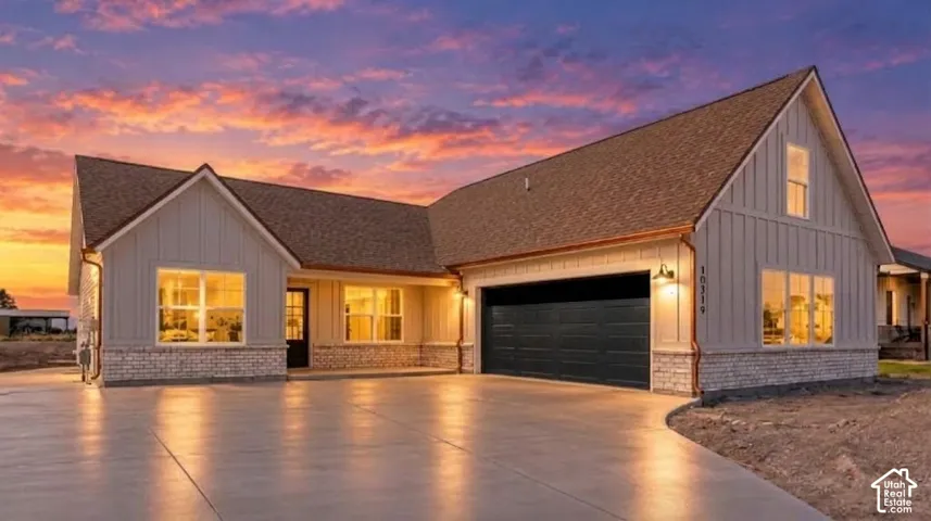 Contemporary exterior featuring board and batten siding, stone accents, a dark-paneled garage door, and a spacious paved driveway
