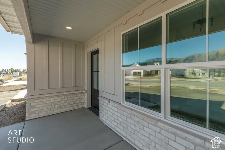Covered entry featuring plank siding, white brick accent, concrete porch, and multi-pane windows