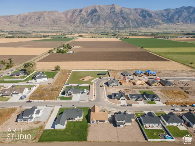 Expansive mountain backdrop with a developing neighborhood featuring completed homes, properties under construction, and undeveloped lots