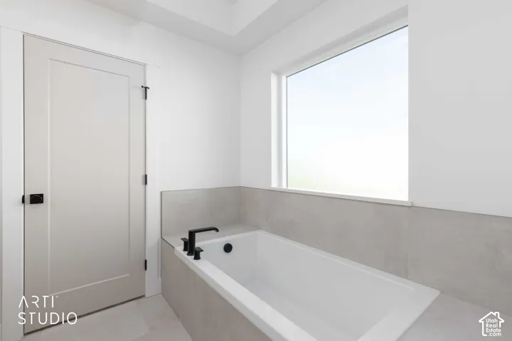 Built-in soaking tub with matte black fixtures, integrated tile surround, and a large window