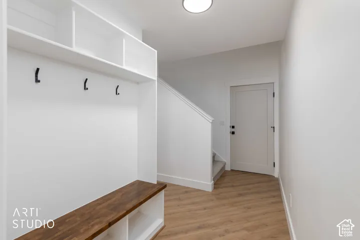 Built-in storage bench with wood-finish top, integrated shelving, and black coat hooks.  Stairs to guest suite in loft