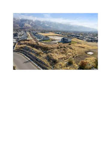 Expansive undeveloped land with a paved street frontage, surrounded by residential properties and a distant mountain range