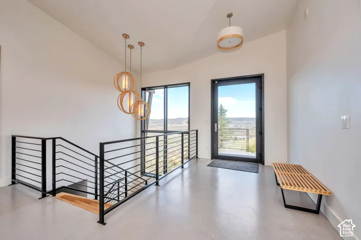 Vaulted ceilings, large windows, contemporary balustrade, wood-finish flooring, and a modern pendant light fixture