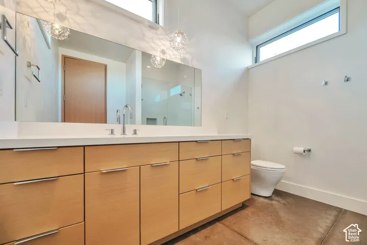 Full-width vanity with light wood-finish cabinetry, white countertop, and a chrome faucet
