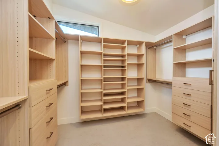 Custom closet system featuring light wood-finish cabinetry, built-in shelving, integrated drawers with linear hardware, and hanging rods