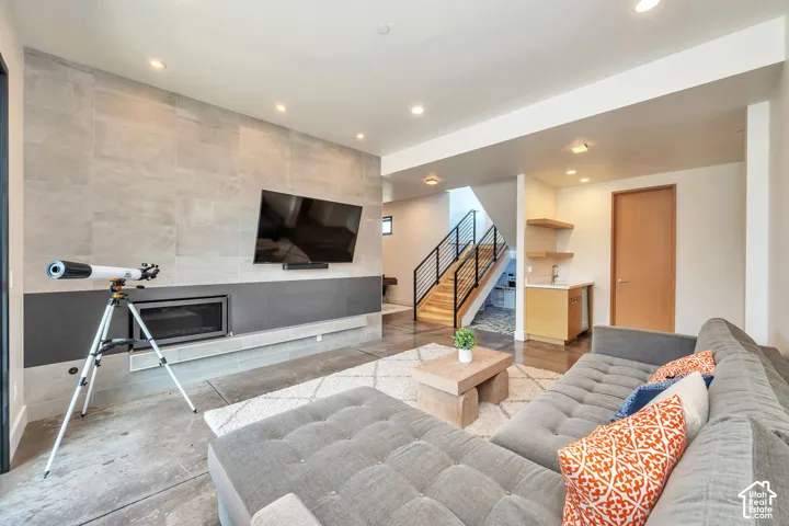 Integrated fireplace with tiled surround, wood-finish flooring, recessed lighting, and a built-in wet bar