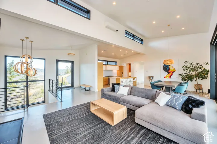 Vaulted ceilings, expansive windows, multiple recessed light fixtures, a durable hard surface floor, and a kitchen featuring light wood-finish cabinetry