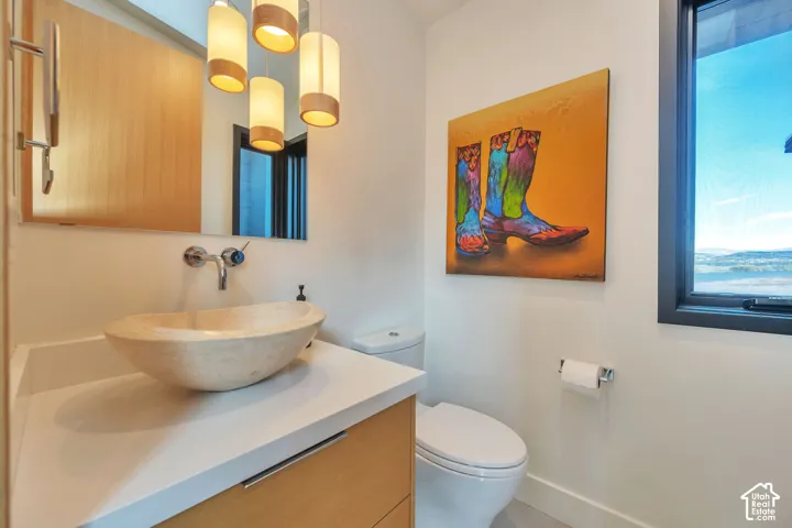 Contemporary vanity with wood-finish cabinetry, a stone vessel sink, and wall-mounted faucet