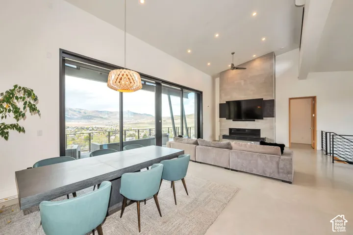 Vaulted ceilings with recessed lighting, floor-to-ceiling sliding glass doors, a stone-clad fireplace, and an open-concept living space