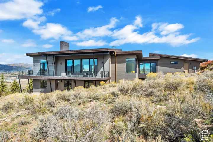 Multi-level contemporary exterior with extensive glazing, expansive balcony featuring glass railings, and a prominent chimney