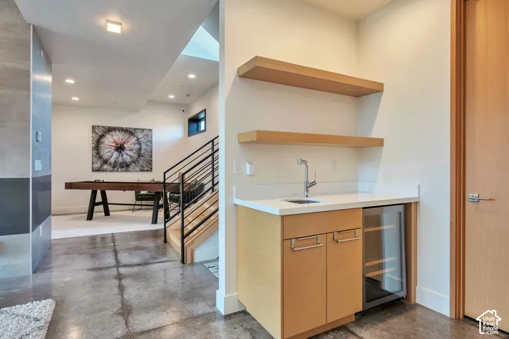 Built-in wet bar with wood-finish cabinetry, white countertop, and under-counter beverage cooler