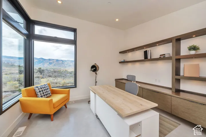 Large windows showcasing mountain scenery, built-in shelving with integrated lighting, recessed ceiling lighting, and hard-surface flooring