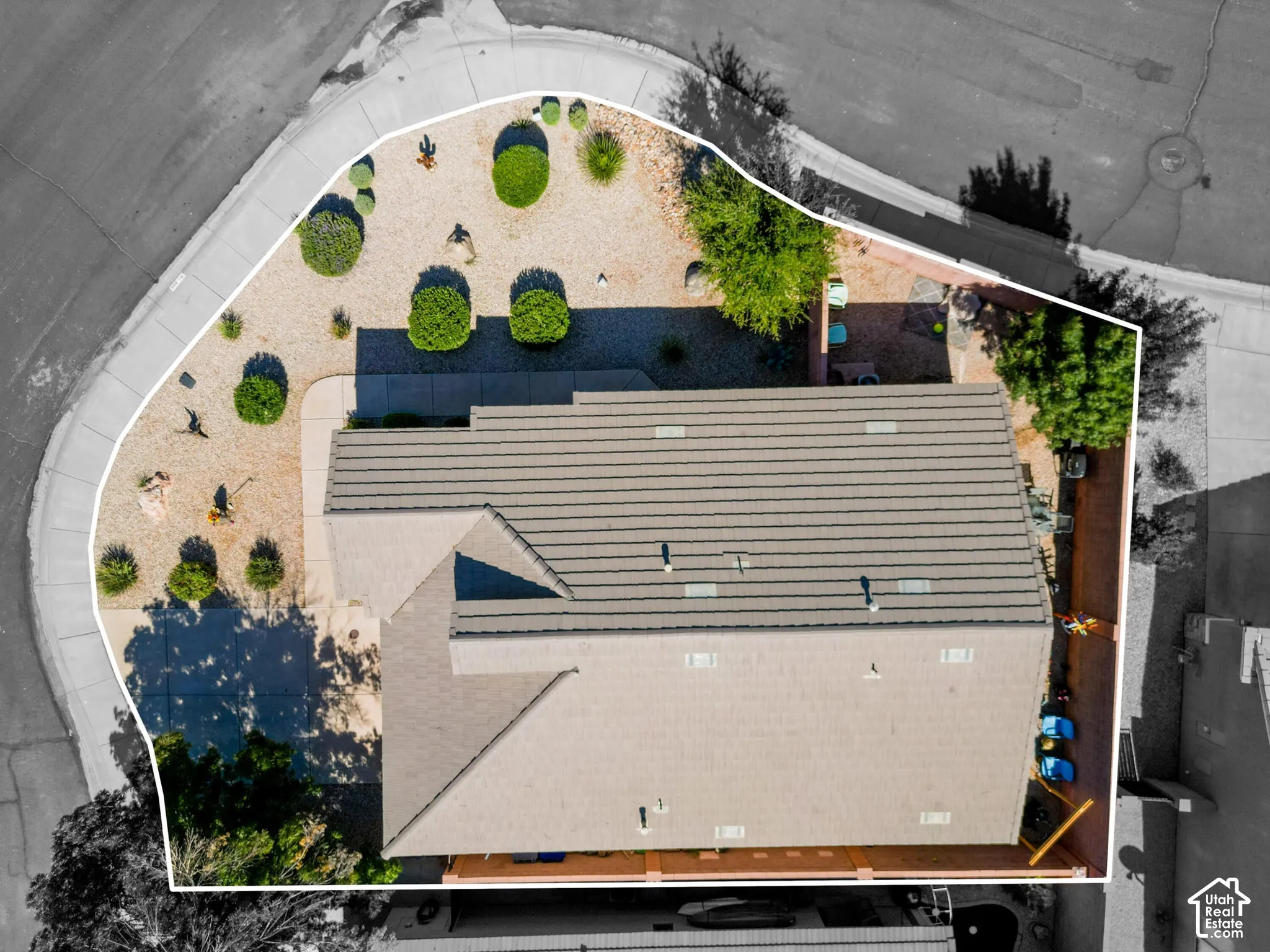 Property featuring a neutral-toned roof, desert landscaping, and a paved driveway