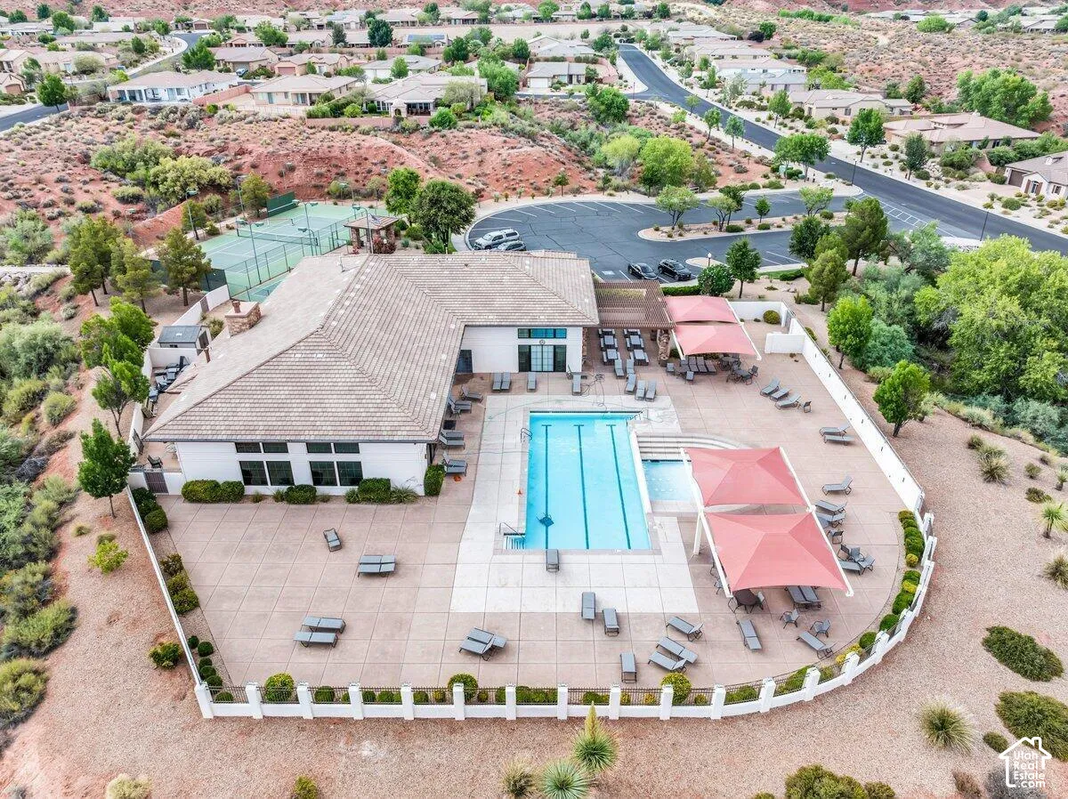 Community clubhouse featuring a swimming pool, expansive paved patio, multiple shade structures, and adjacent tennis courts
