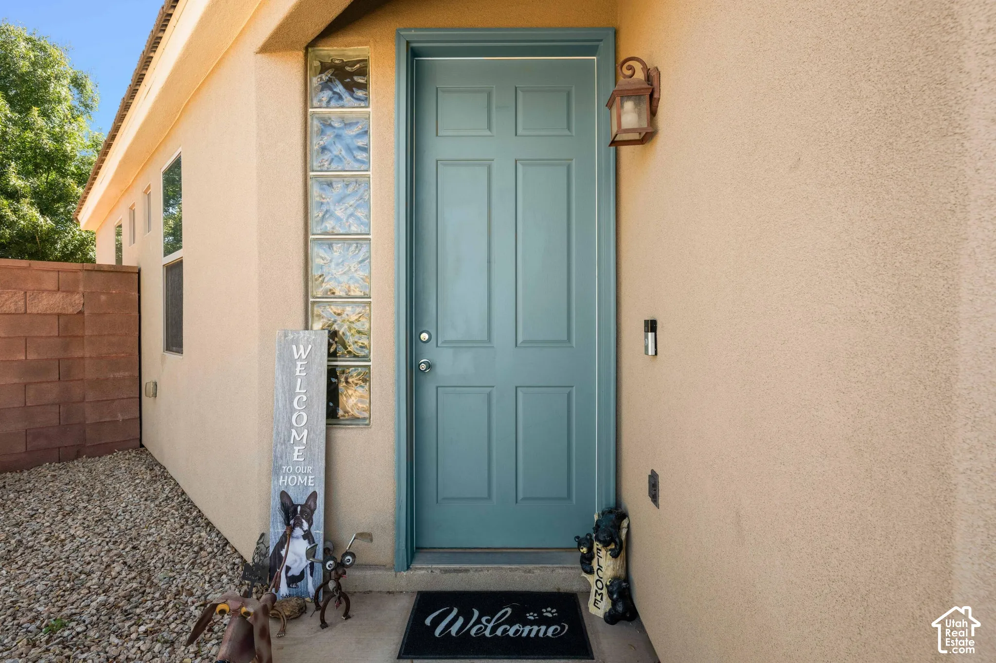 Stucco exterior featuring a panel-style entry door, decorative glass block accents, and an exterior wall lantern
