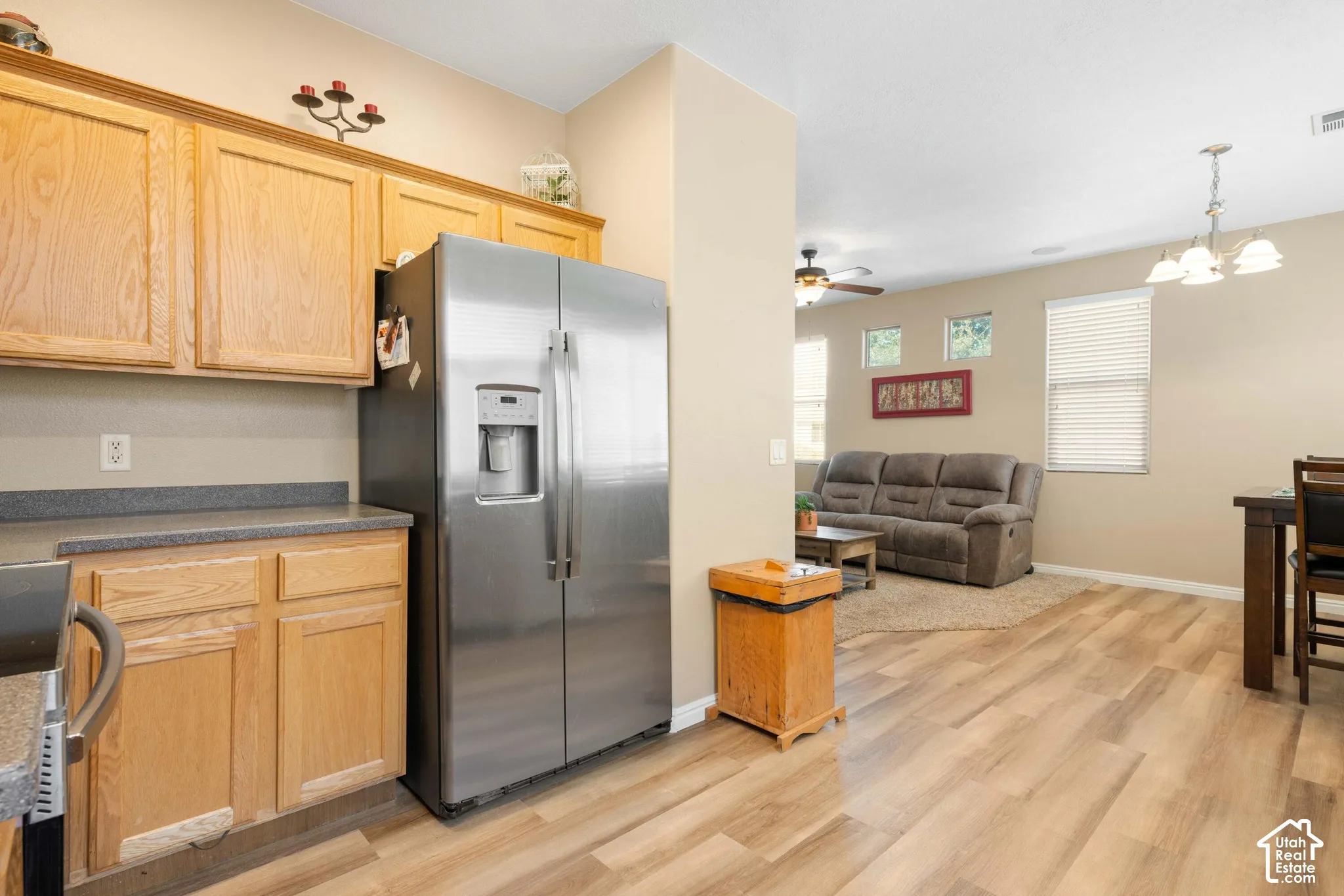 Stainless steel side-by-side refrigerator, wood-finish flooring, and natural wood cabinetry with a laminate countertop