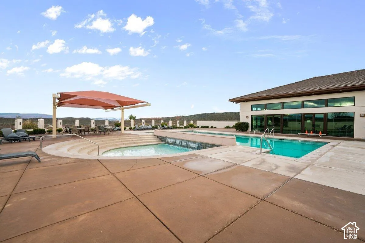 Expansive outdoor pool area featuring a large pool, a separate wading pool, and a shaded seating area