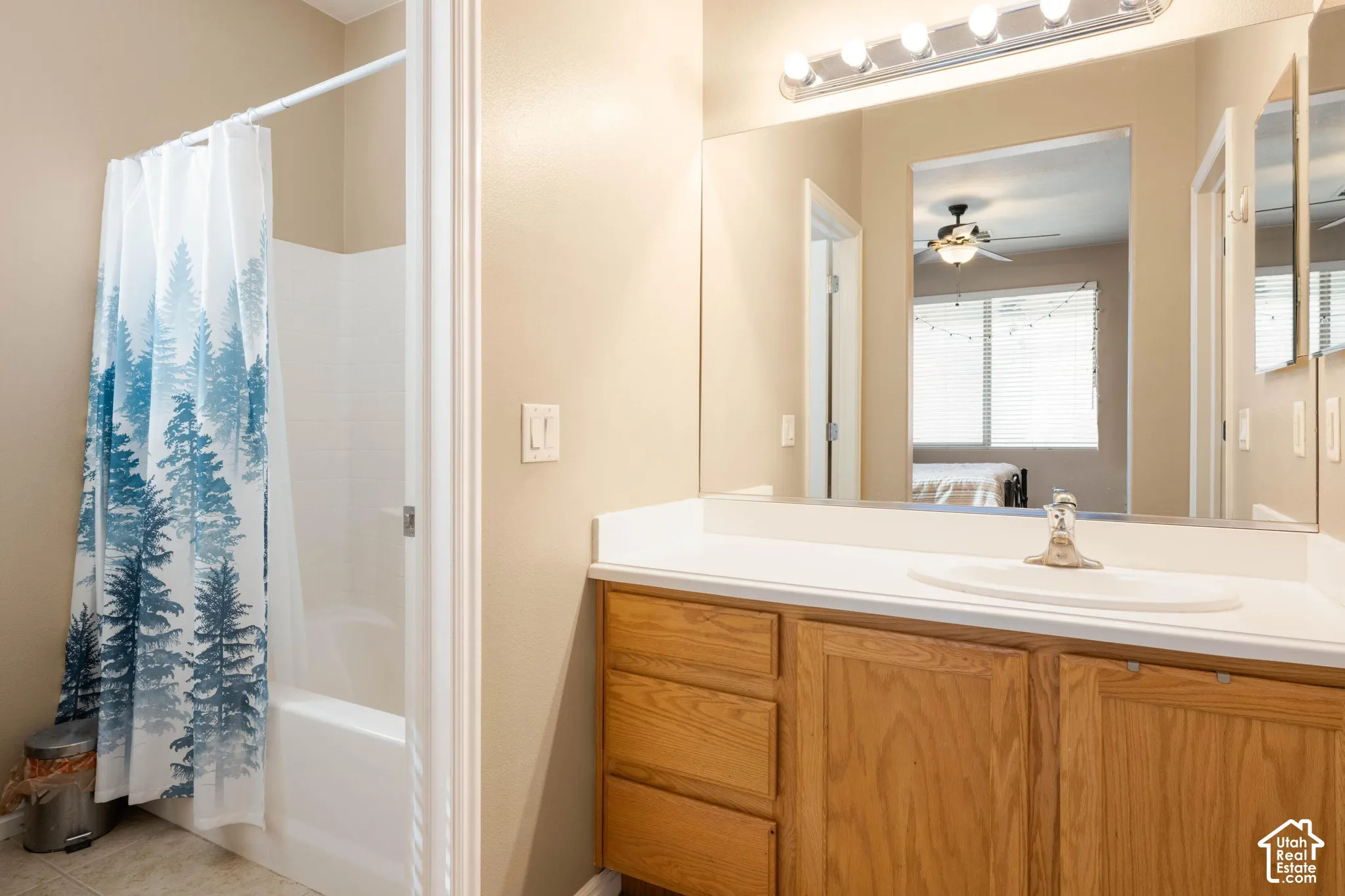 Bathroom featuring a white bathtub, a single vanity with a white countertop and integrated sink, and wood-finish cabinetry