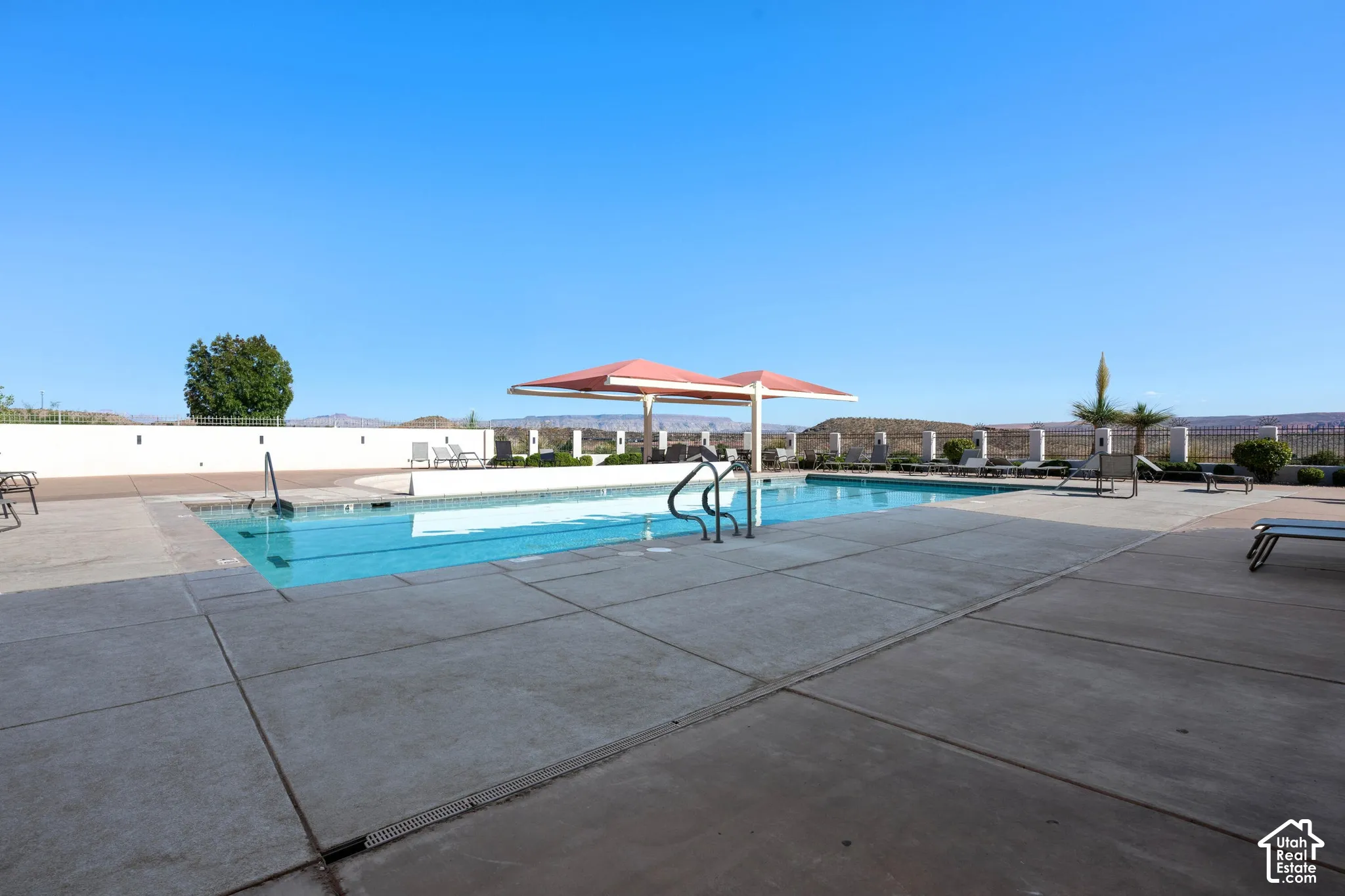 Swimming pool with concrete decking and a red shade structure