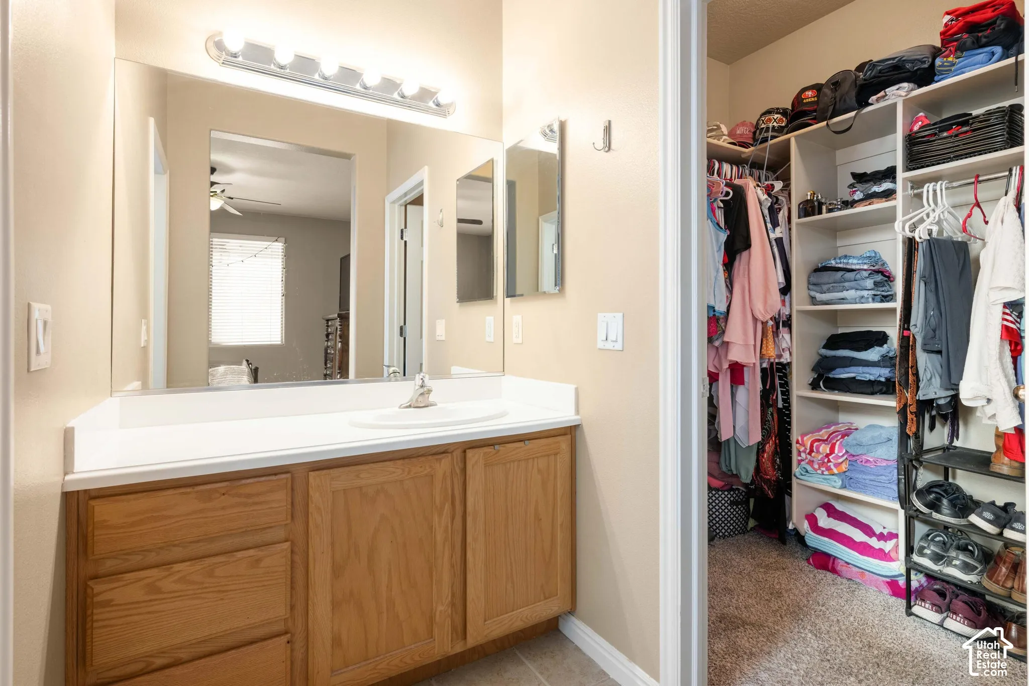 Vanity with a single basin sink, light wood-finish cabinetry, and a large wall-mounted mirror
