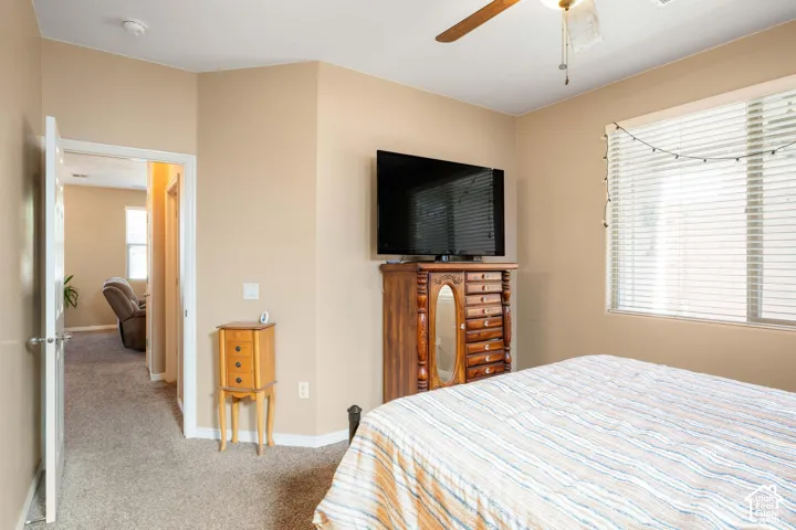 Neutral-toned walls, ceiling fan, and carpeted flooring