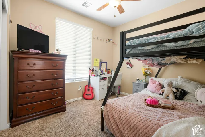 Carpeted bedroom featuring a ceiling fan and window with blinds