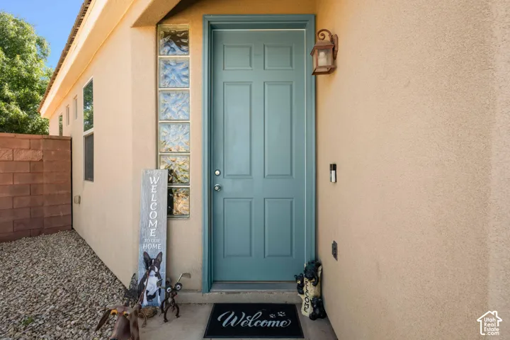 Stucco exterior featuring a panel-style entry door, decorative glass block accents, and an exterior wall lantern