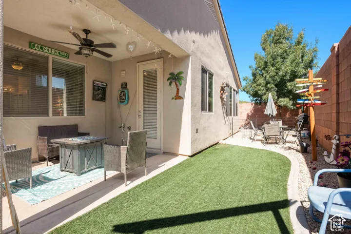 Patio with a ceiling fan, direct exterior access, and an adjacent low-maintenance artificial turf area