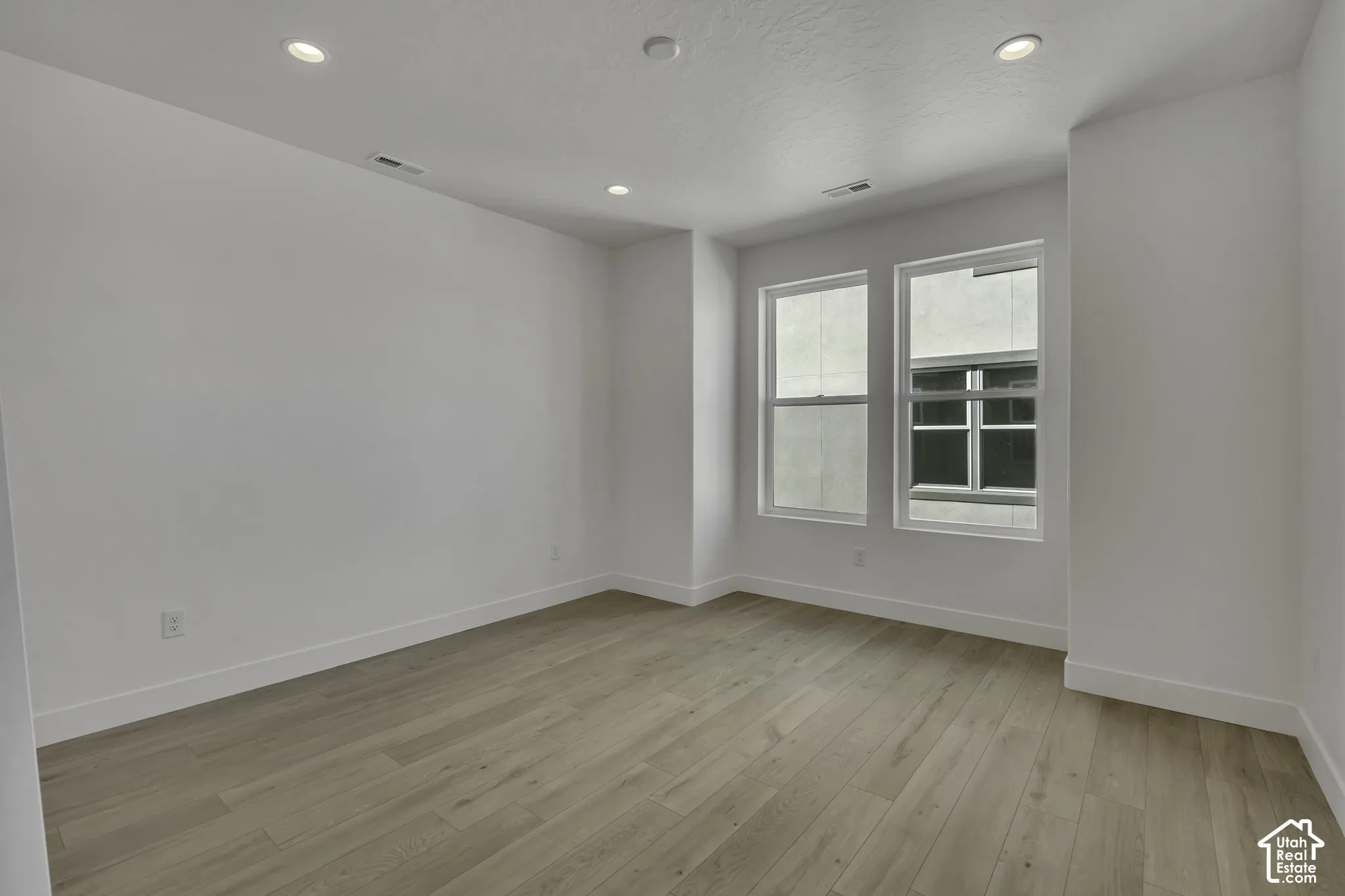 Recessed ceiling lighting with a neutral color palette, wood-finish flooring, and white trim