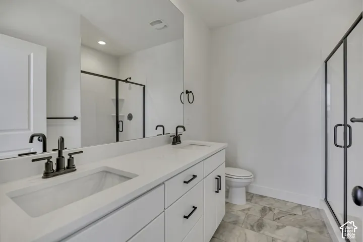 Double vanity with integrated sinks, white cabinetry, matte black hardware, glass-enclosed shower, and large format tile flooring