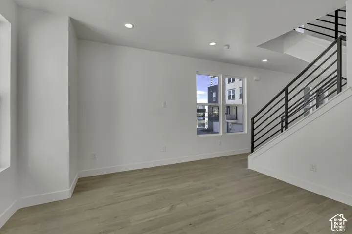 Recessed lighting, wood-finish flooring, white walls, and a modern staircase with dark railings