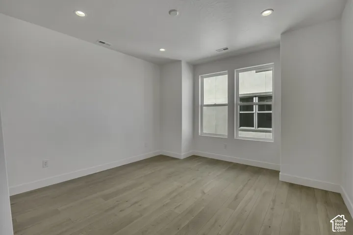 Recessed ceiling lighting with a neutral color palette, wood-finish flooring, and white trim