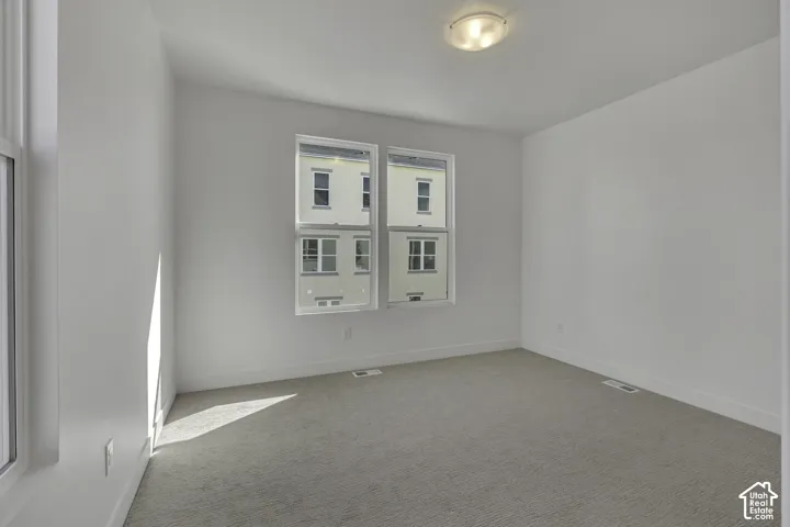 Bright room featuring light gray carpeting, white walls, and multiple windows