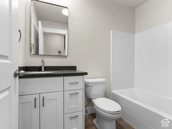 White vanity with shaker-style cabinetry, dark countertop, and rectangular undermount sink