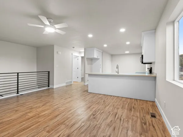 Open-concept living space with wood-finish flooring, recessed lighting, and a contemporary ceiling fan
