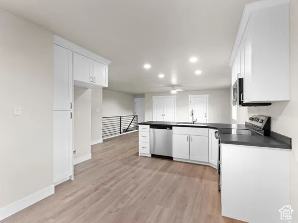 Kitchen featuring white shaker cabinetry, dark countertops, wood-finish flooring, stainless steel appliances, and recessed lighting