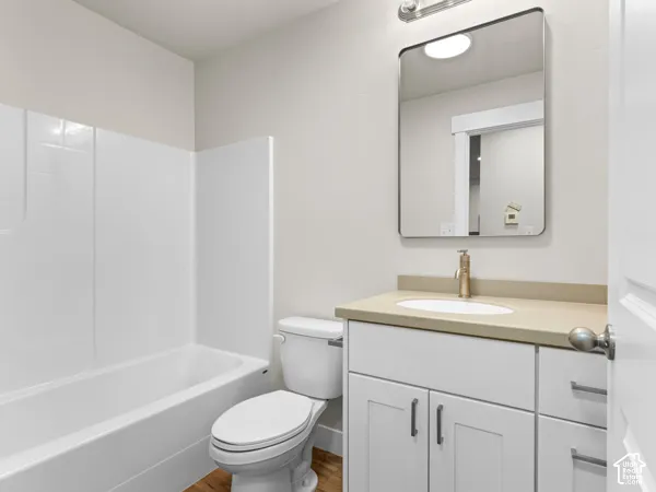 White vanity with shaker-style cabinetry, an integrated sink, and a gold-finish faucet