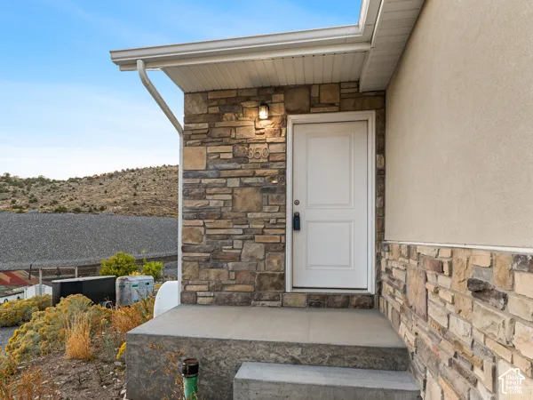 Entryway featuring a white paneled door, stone facade, stucco exterior, and concrete steps